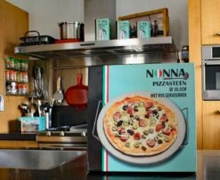 Nonna Pizzasteen Ø30,5 Met RVS Serveerrek - Stenen Pizzaplaat / Ovenplaat (11mm Dik) Voor Oven En Barbecue (BBQ) - Maximaal 600 Graden Celcius -Optimaal Barbecue Winkel 1200x985